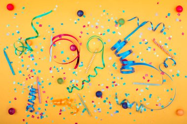 Flamalar, konfeti ve boynuzları sarı arka plan üzerinde renkli parti öznitelikleri. Düz yalan. Yüksek çözünürlüklü fotoğraf.