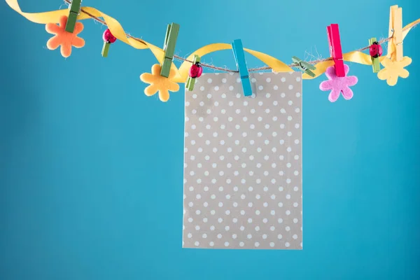 Lege kaart gevestigd op de waslijn. Ruimte voor formuleringen te kopiëren. Vastgemaakt met bloem pinnen. Blauwe, oranje achtergrond. Hoge resolutie foto. — Stockfoto