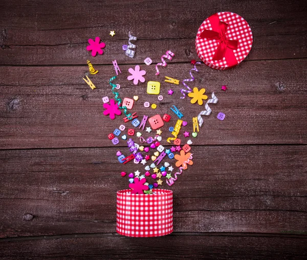 Exploderende viering rode geruite geschenkdoos op een houten achtergrond. Vakantie concept. — Stockfoto