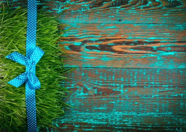 Linia niebieski ozdoba na trawie szczotkowanego niebieski panel drewniany. Prezenty lub cocept uroczystości. Układ płaski. — Zdjęcie stockowe