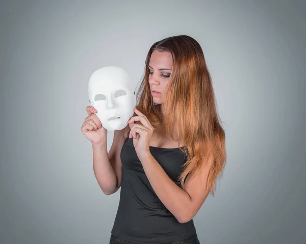 Jeune femme émotionnelle tenant un masque dans une pose des mains en studio sur — Photo