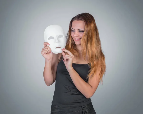 Молодая эмоциональная женщина держит маску в руках позировать в студии на — стоковое фото