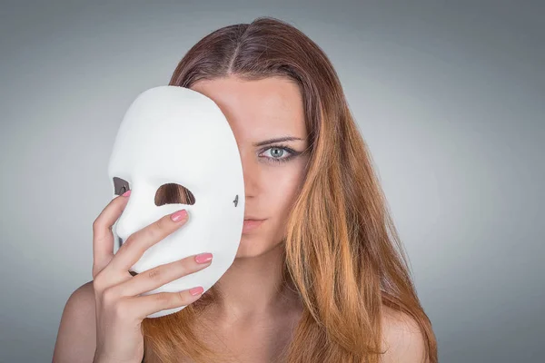 Young emotional woman holding mask in a hands pose in studio on