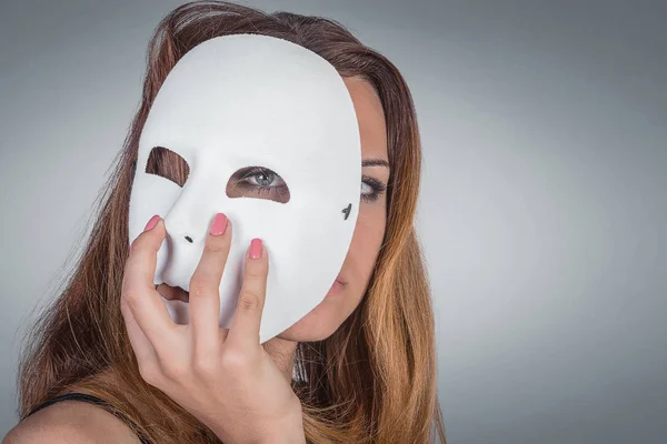 Young emotional woman holding mask in a hands pose in studio on