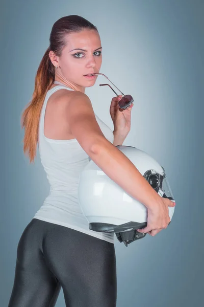 Beautiful young woman with moto helmet in studio on blue backgro — Stock Photo, Image