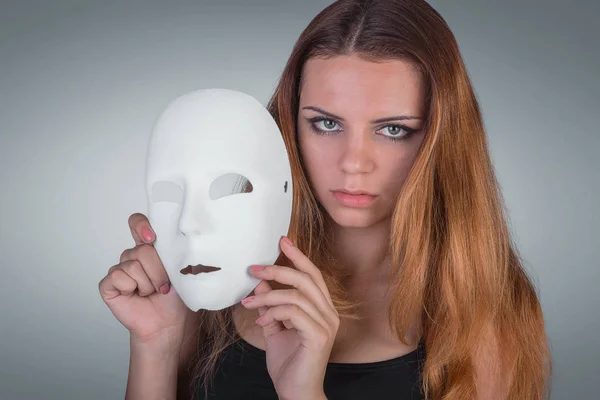 Unga känslomässiga kvinna som håller masken i en händer pose i studio — Stockfoto