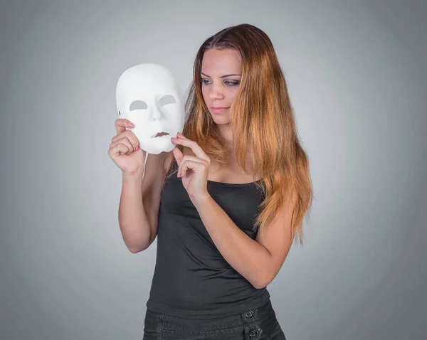 Young emotional woman holding mask in a hands pose in studio on