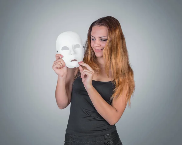 Young emotional woman holding mask in a hands pose in studio on