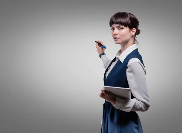 Улыбающаяся деловая женщина держит планшет на сером фоне. Студия — стоковое фото