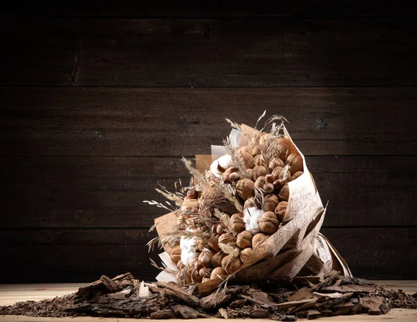 Букет коричневих горіхів на фоні дерева в обгортці паперу — стокове фото