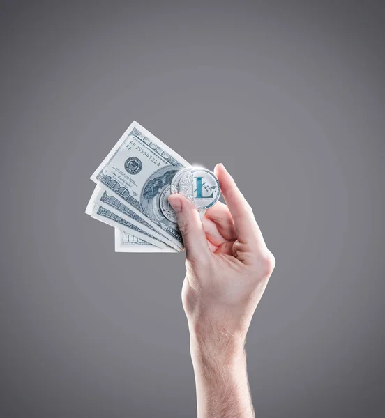 Hand with coins of litecoins and dollar bills on the gray background. Digital money exchange cryptocurrency concept — Stock Photo, Image