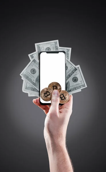 Hand som håller mobiltelefon med tom skärm och bitcoin mynt, dollarsedlar mot den bakgrunden blured. Digital övervakning, kontroll och pengar utbyta kryptovaluta koncept — Stockfoto