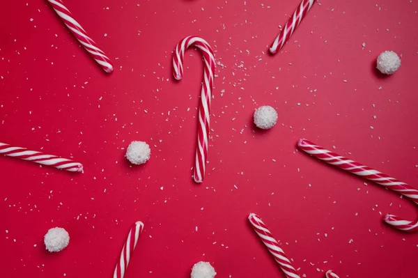 Καραμέλες και άσπρες μπάλες καραμέλας καρύδας σε κόκκινο φόντο. Χριστουγεννιάτικη κάρτα. Ευτυχισμένο το νέο έτος. — Φωτογραφία Αρχείου