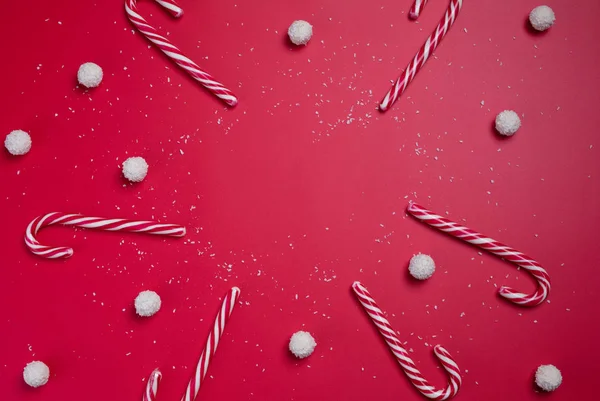 Καραμέλες και άσπρες μπάλες καραμέλας καρύδας σε κόκκινο φόντο. Χριστουγεννιάτικη κάρτα. Ευτυχισμένο το νέο έτος. — Φωτογραφία Αρχείου