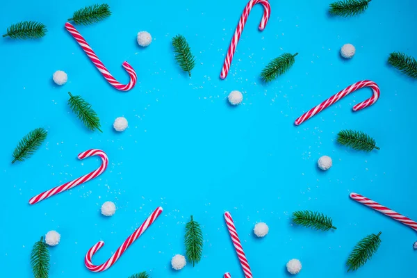 Cukierki z gałązkami jodły na niebieskim tle. Świąteczna pocztówka. Szczęśliwego Nowego Roku — Zdjęcie stockowe