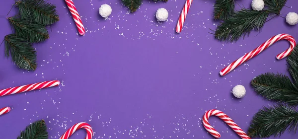 Candies with coconut white balls are in a circle on a purple background and branches fir. Christmas postcard. Happy New Year concept — 스톡 사진