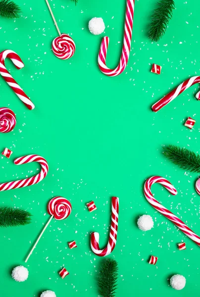 緑の背景に枝のモミのキャンディー・ケーンズとロリポップ。ココナッツボールクリスマスポストカードあけましておめでとうございます。 — ストック写真