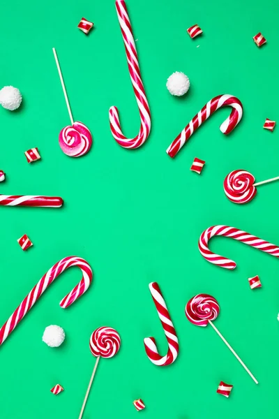 Candy Canes i lizaki z kulkami kokosowymi są w kształcie koła na zielonym tle. Świąteczna pocztówka. Szczęśliwego Nowego Roku — Zdjęcie stockowe