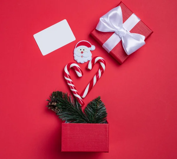 クリスマスカード赤の背景に招待状。スイーツと一緒にサプライズボックス。あなたのための興味深い提案. — ストック写真