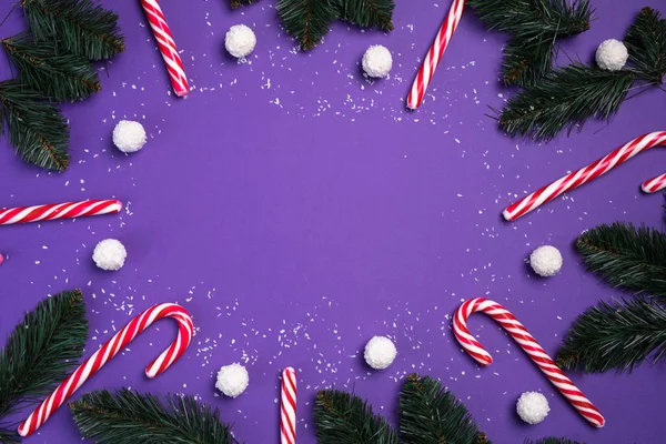 Cukierki z białymi kulkami kokosowymi są w kole na fioletowym tle i gałązki jodły. Świąteczna pocztówka. Szczęśliwego Nowego Roku — Zdjęcie stockowe