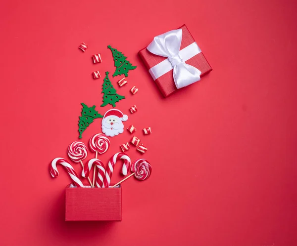 Christmas card. Invitation card on a red background. Surprise box with sweets. Interesting proposition for you.