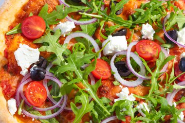 İtalyan sıcak pizzası, domates, roka, peynir Feta, siyah zeytin ve soğan beyaz arka planda izole edilmiş.