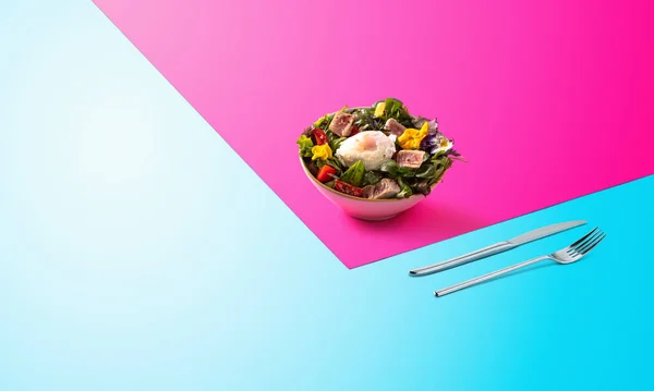 Ensalada con aguacate, rúcula, espinacas, carne y un huevo en el medio. Decorado con flores. Fondo soleado colorido. Sabroso menú para la comida europea . — Foto de Stock