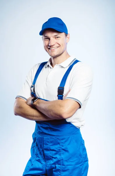 Retrato de un joven trabajador vestido de uniforme azul con las manos cruzadas. Aislado sobre fondo gris con espacio de copia. Expresión de rostro humano, emoción. Concepto empresarial . — Foto de Stock