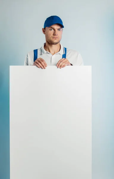 Imagem falsa de um jovem trabalhador indignado segurando uma bandeira branca vazia. Fundo branco ou azul. Conceito de negócio . — Fotografia de Stock