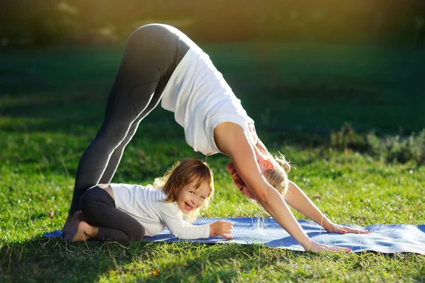 Yoga family practicing yoga in the park having fun