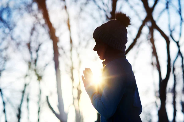 Silhouette of a meditating woman in the forest with a sun light