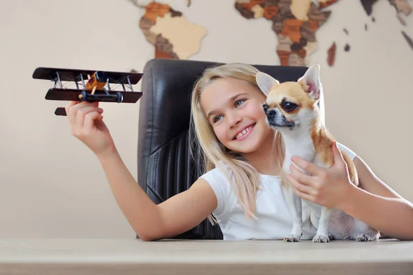 Happy girl showing her dog an old style airplane