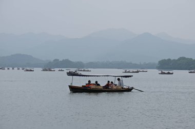 Hangzhou / Çin - 05.16.2019: Su turistleri. İnsanlar Çin tarzında eski bir teknede yelken açıyorlar..