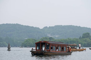 Hangzhou / Çin - 05.16.2019: Su turistleri. İnsanlar Çin tarzında eski bir teknede yelken açıyorlar..