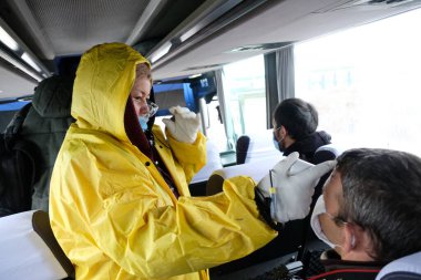 Almaty / Kazakistan - 04.09.2020: Bir sağlık görevlisi otobüs yolcularının sıcaklığını kontrol ediyor