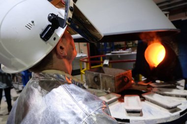 Magadan / Rusya - 03.20.2019: Tulumlu bir işçi metalin erimesini izliyor