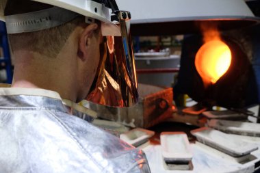 Magadan / Rusya - 03.20.2019: Tulumlu bir işçi metalin erimesini izliyor