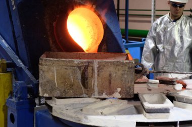 Magadan / Rusya - 03.20.2019: Tulumlu bir işçi metalin erimesini izliyor