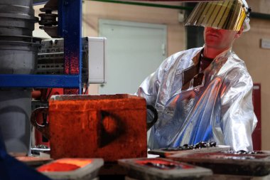 Magadan / Rusya - 03.20.2019: Tulumlu bir işçi metalin erimesini izliyor