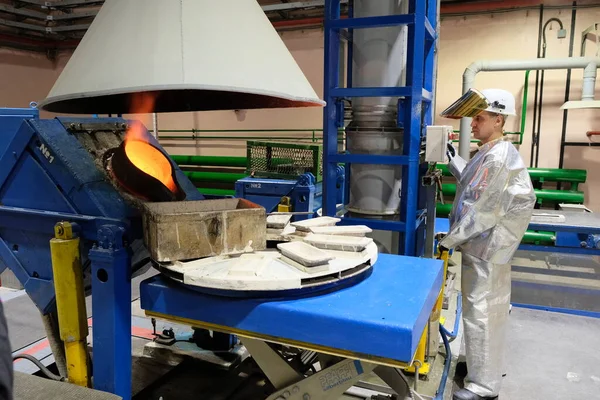Magadan / Rusya - 03.20.2019: Tulumlu bir işçi metalin erimesini izliyor