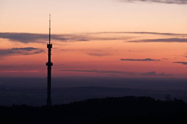 Kok Tobe TV kulesi, yüksek bir tepede, Kazakistan 'ın Almatı şehrinin üzerindeki ağaçlarla birlikte. Gün batımından sonra.