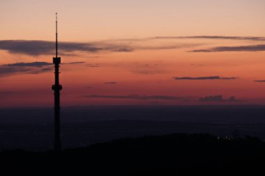 Kok Tobe TV kulesi, yüksek bir tepede, Kazakistan 'ın Almatı şehrinin üzerindeki ağaçlarla birlikte. Gün batımından sonra.