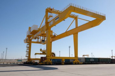 Khorgos / Kazakistan - 10.06.2018: Lojistik merkezinde konteynırlar boşaltılıyor. Makineler ve turnalar metal kutuları sürüklüyor.