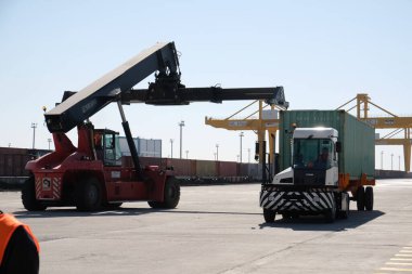 Khorgos / Kazakistan - 10.06.2018: Lojistik merkezinde konteynırlar boşaltılıyor. Makineler ve turnalar metal kutuları sürüklüyor.