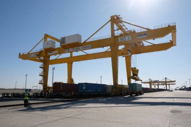Khorgos / Kazakistan - 10.06.2018: Lojistik merkezinde konteynırlar boşaltılıyor. Makineler ve turnalar metal kutuları sürüklüyor.
