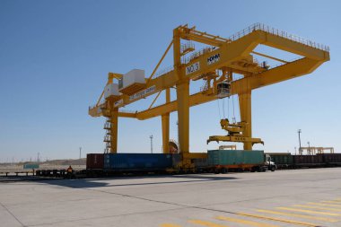 Khorgos / Kazakistan - 10.06.2018: Lojistik merkezinde konteynırlar boşaltılıyor. Makineler ve turnalar metal kutuları sürüklüyor.
