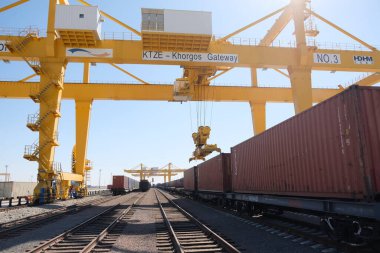 Khorgos / Kazakistan - 10.06.2018: Lojistik merkezinde konteynırlar boşaltılıyor. Makineler ve turnalar metal kutuları sürüklüyor.