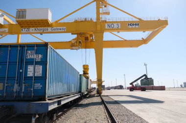 Khorgos / Kazakistan - 10.06.2018: Lojistik merkezinde konteynırlar boşaltılıyor. Makineler ve turnalar metal kutuları sürüklüyor.