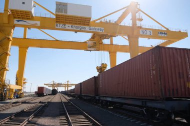 Khorgos / Kazakistan - 10.06.2018: Lojistik merkezinde konteynırlar boşaltılıyor. Makineler ve turnalar metal kutuları sürüklüyor.