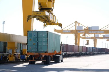 Khorgos / Kazakistan - 10.06.2018: Lojistik merkezinde konteynırlar boşaltılıyor. Makineler ve turnalar metal kutuları sürüklüyor.
